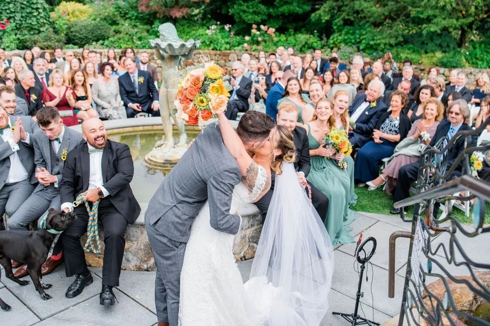 Guests on the terrace below cheer as the couple kisses above them