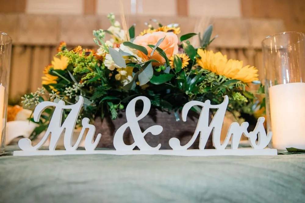 Sunflower centerpiece behind a white Mr and Mrs sign at the sweetheart table