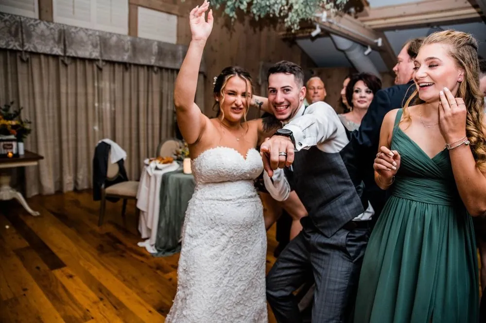Caroline dances with one arm raised as Zachary points at the camera