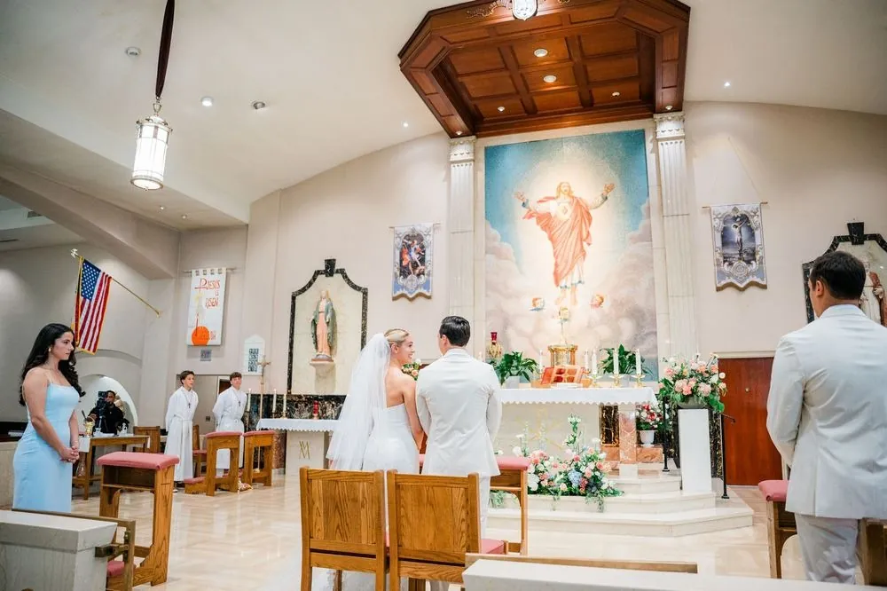 Wide view of the church altar and painted mural as the couple stand before the priest
