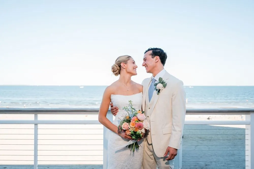 Chris and Carmen smile at each other on the pavilion deck railing above the water