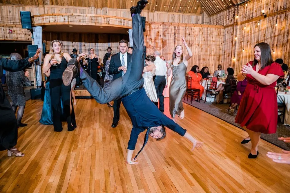 A guest in a dress shirt and tie does a cartwheel across the dance floor