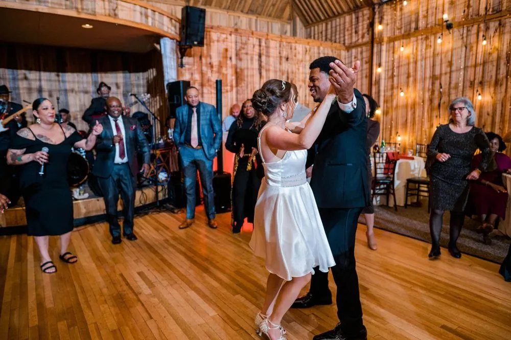 Guests dance with arms up under the pavilion's string lights