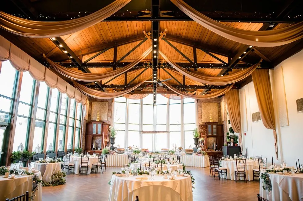 The reception hall with a wood-beamed ceiling, gold fabric swags and tall windows