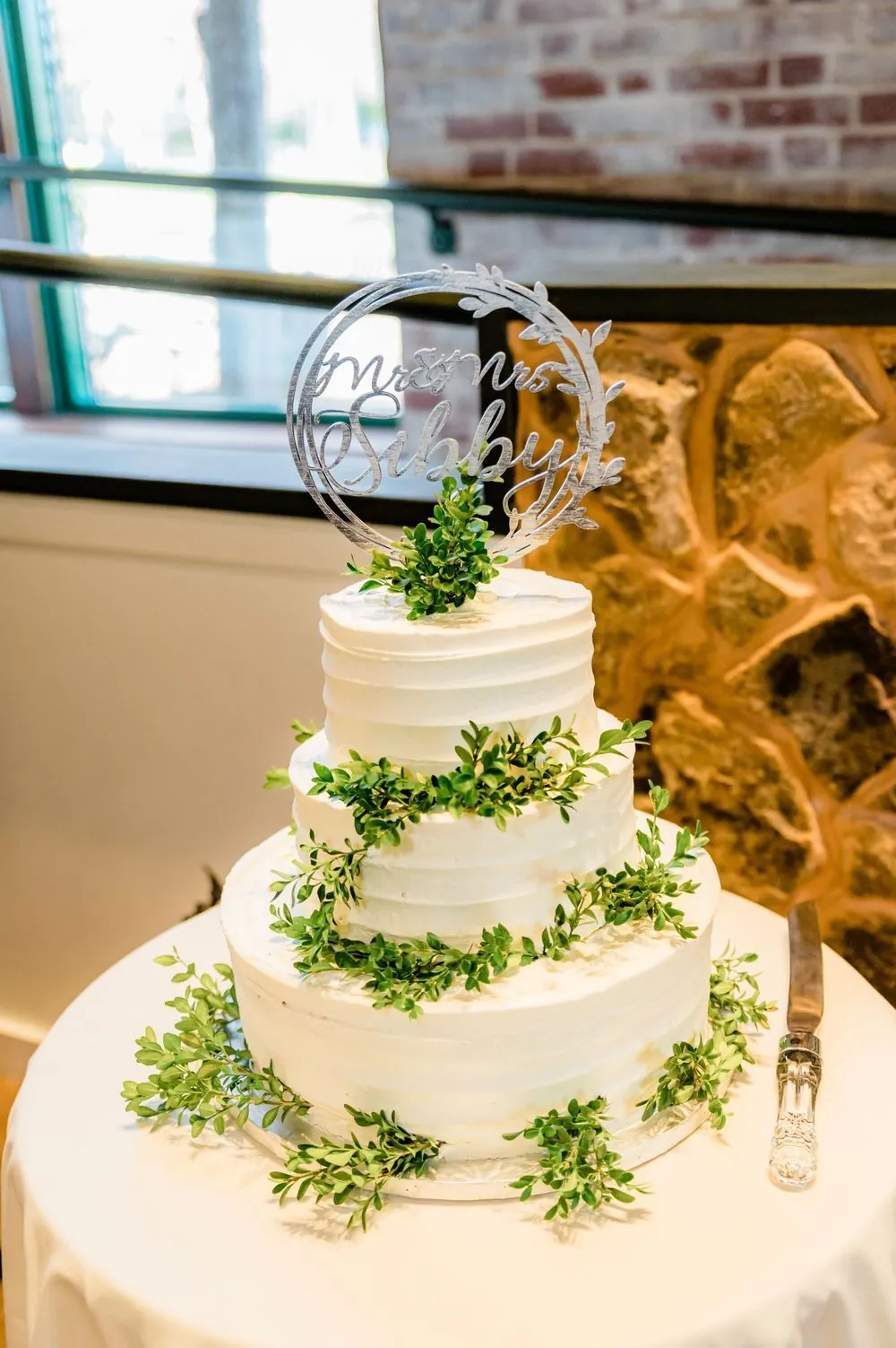 A 3-tier white cake wrapped in trailing greenery