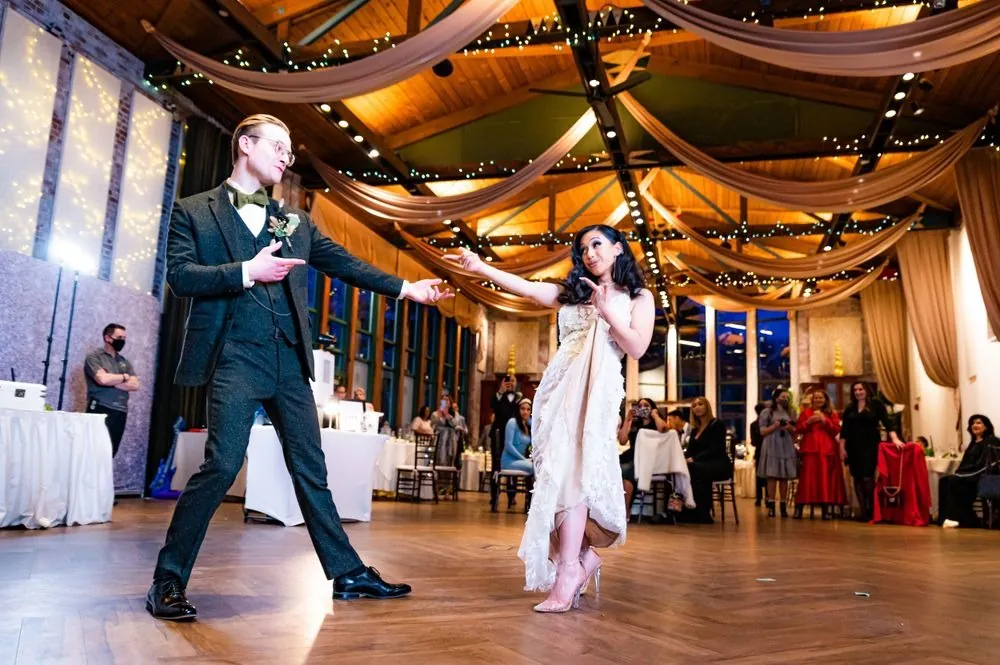 Colin and Victoria strike playful poses during their first dance under the beamed ceiling