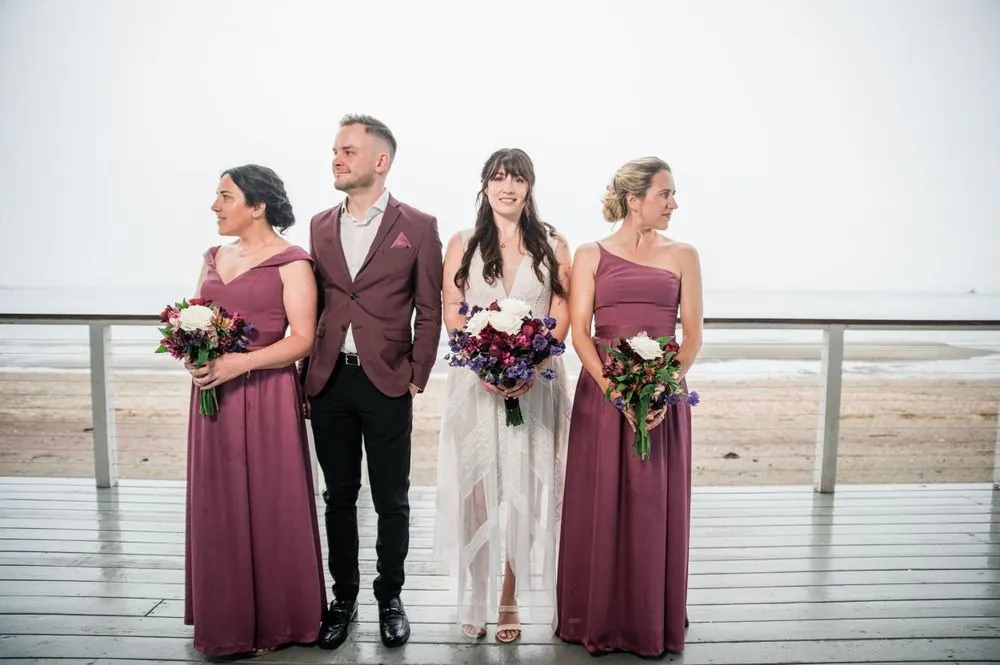 Bride with her bridesmaids in mauve and a friend in a wine jacket on the deck