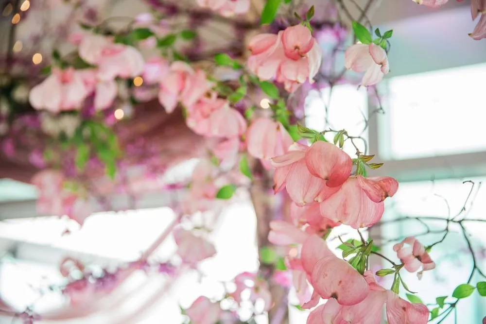 Pink blossoms and greenery woven through the ceremony arch inside the pavilion