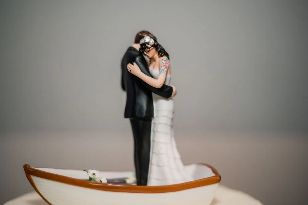 Cake topper of a couple embracing inside a small white rowboat