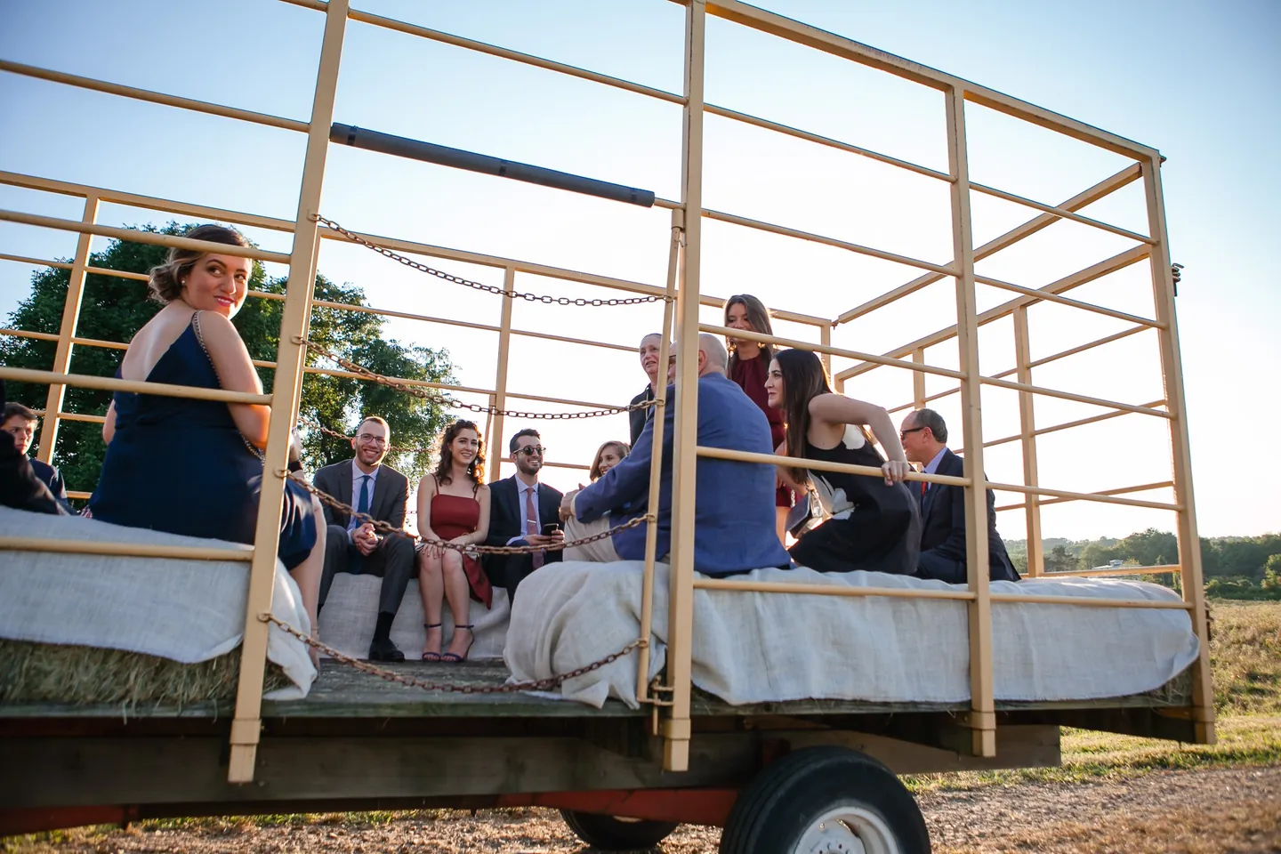Guests ride a hay wagon across the farm in the late afternoon sun