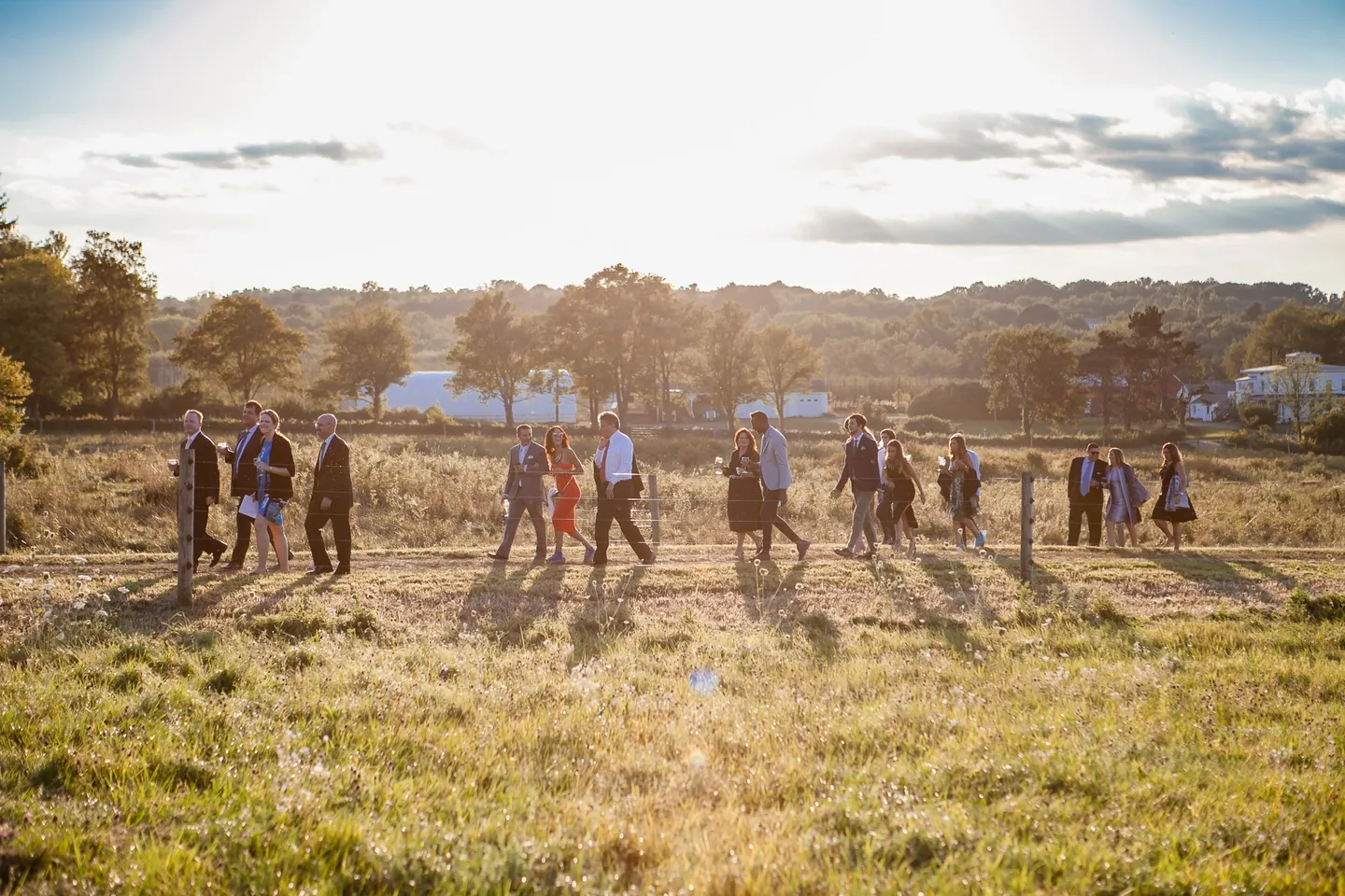 Guests stroll across the open field in silhouette as the sun sets
