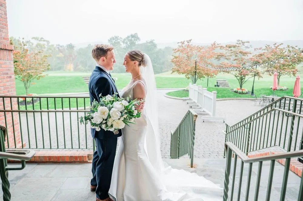 Elizabeth and Colsen face each other on the terrace steps, fall maples and misty fairways behind them