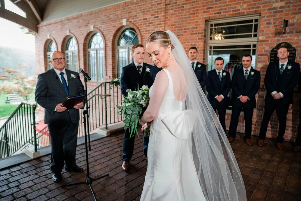 The officiant speaks under the covered porch as the bride and groom hold hands