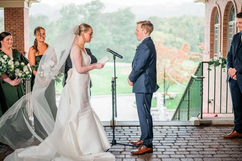 Elizabeth reads her vows to Colsen on the rainy porch, her long veil trailing on the brick