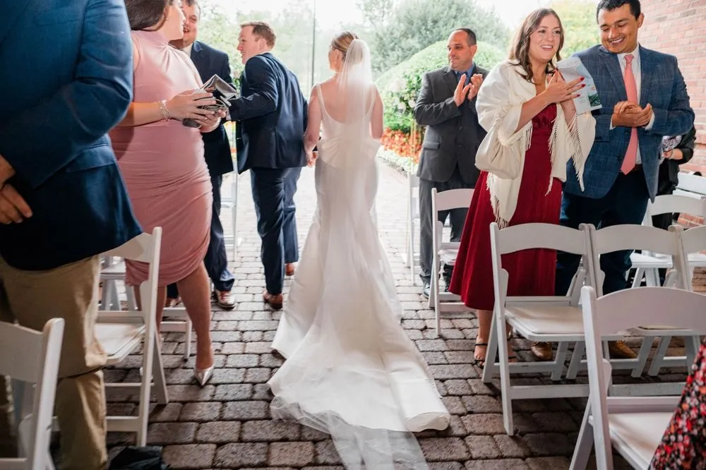 Guests stand and cheer as the newlyweds walk back up the aisle on the porch