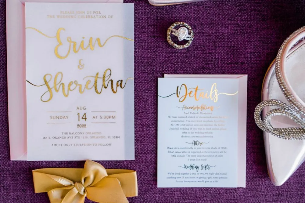 Blush and gold invitation suite with a gold bow on a plum fabric background