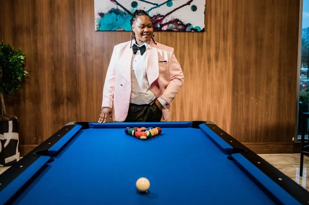 A pink tuxedo pose over a blue felt pool table in a wood-paneled lounge