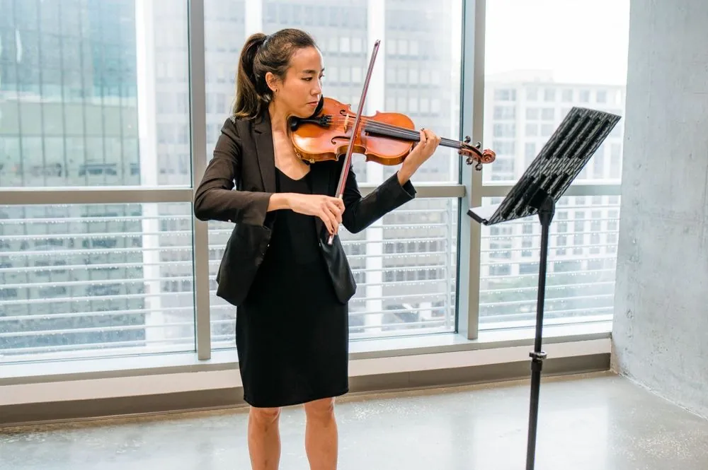 A violinist plays by the windows as guests arrive for the ceremony