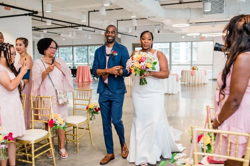 The bride is escorted down the aisle between guests on gold chairs