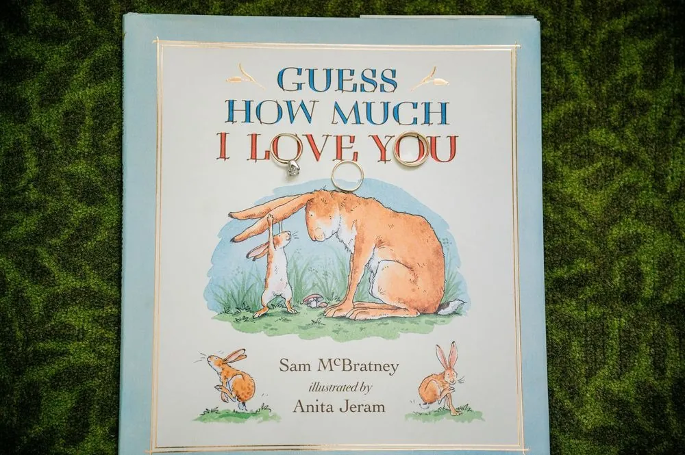 A copy of Guess How Much I Love You laid on a green floral backdrop