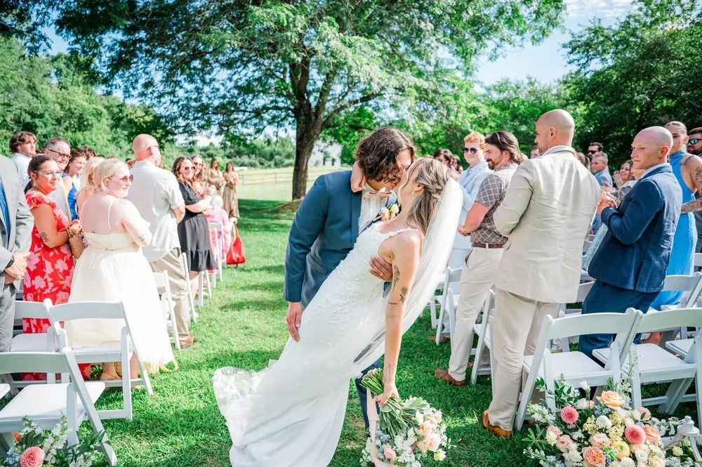 Dom dips Fallon into a kiss in the aisle as guests stand and clap