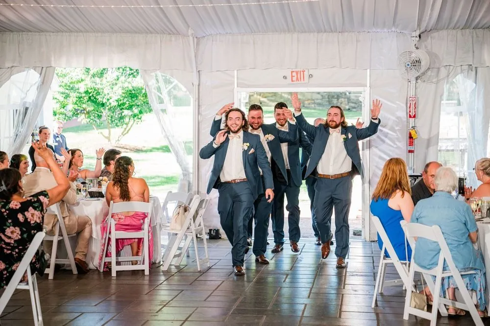 Groomsmen burst into the tent for the grand entrance as guests cheer
