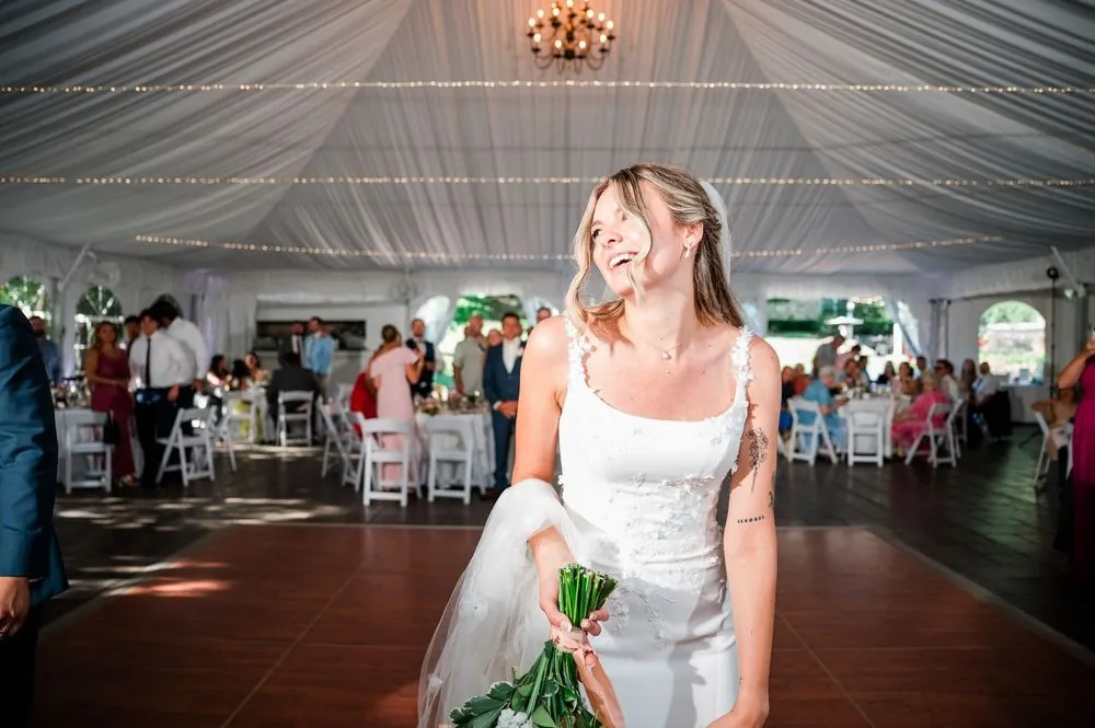 The bride laughs on the dance floor of the draped white tent