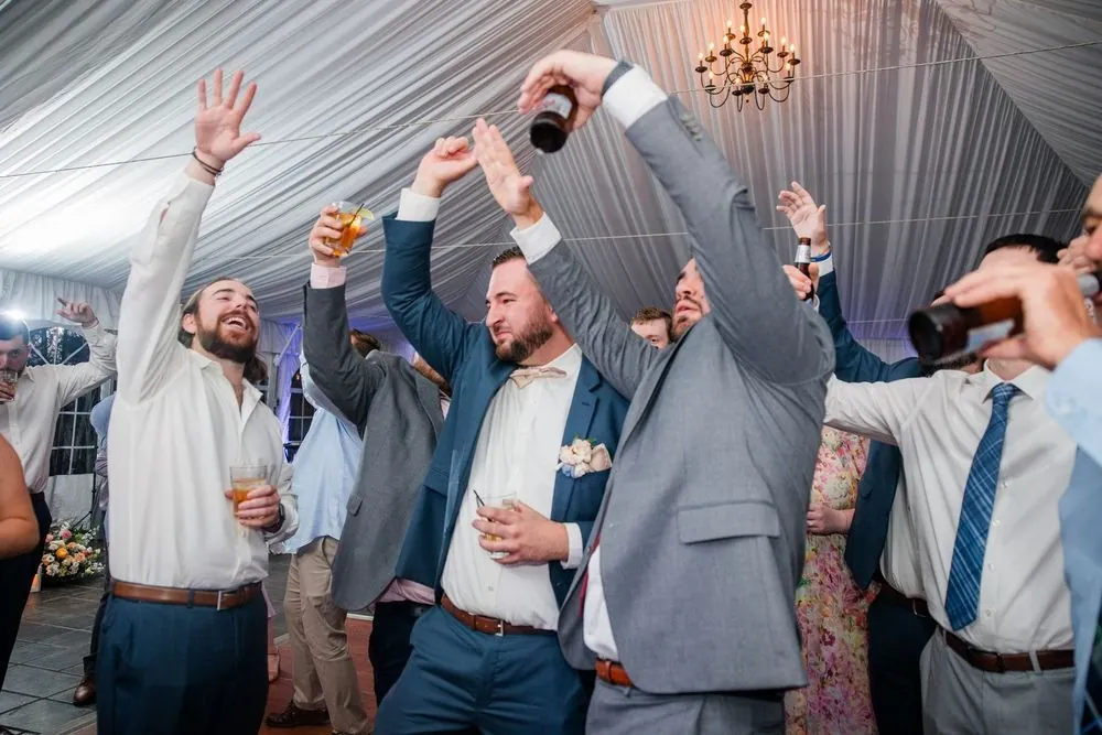 Guests jump with arms raised on the crowded dance floor under the tent
