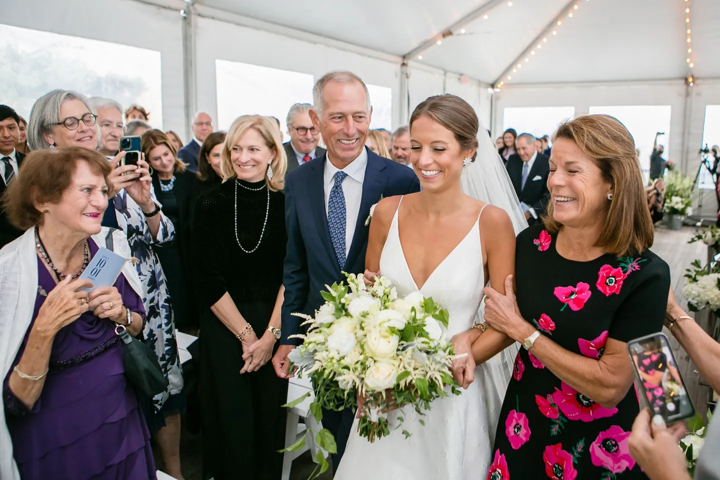 The couple gather with older relatives in the tent, the bride holding her white bouquet