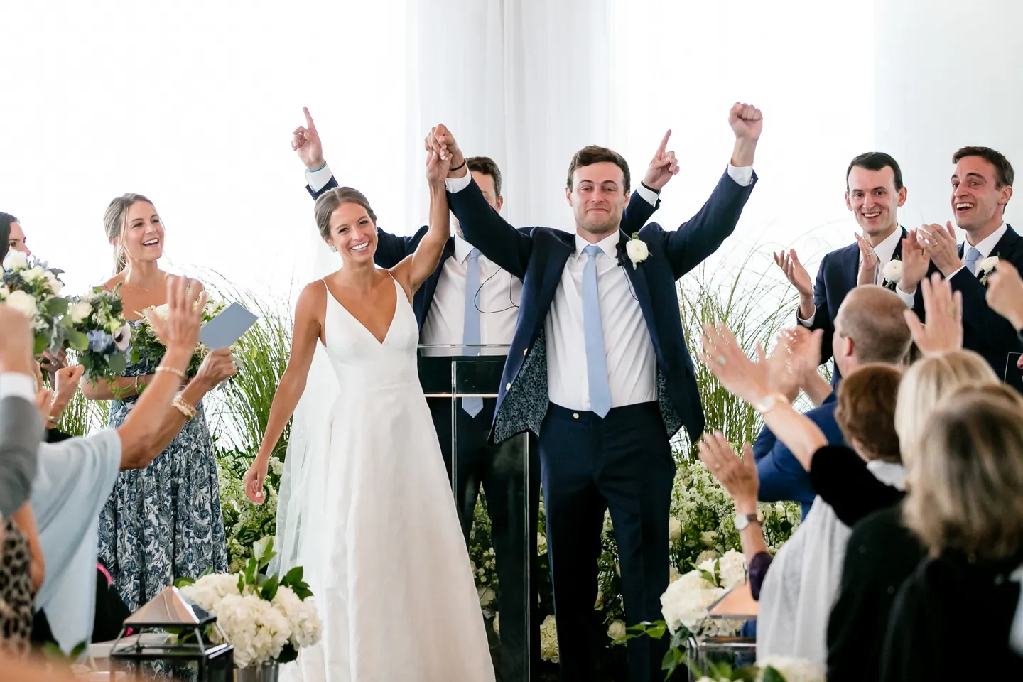 Guests throw their arms up as the couple enters the reception tent