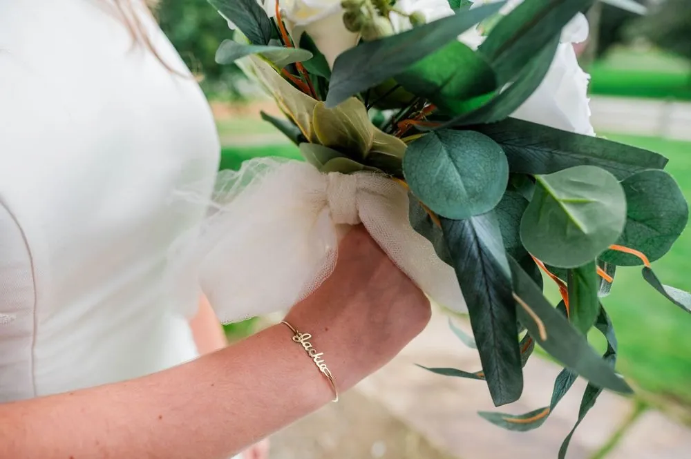 Close view of an engagement ring on the bride's hand against green bouquet leaves