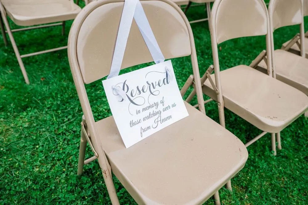 A handwritten reserved sign hanging on a folding chair on the grass