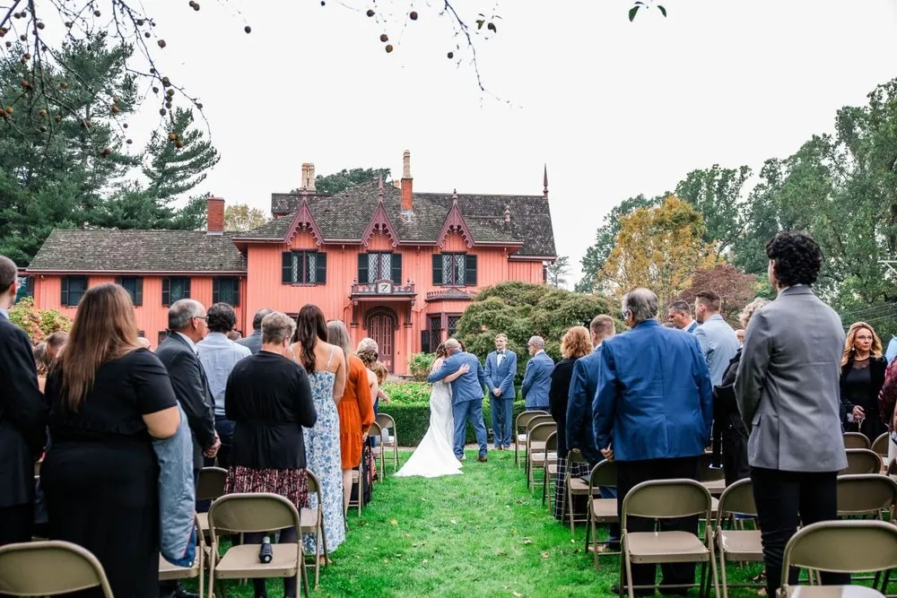 Guests stand on both sides of the aisle as the bride arrives on the lawn