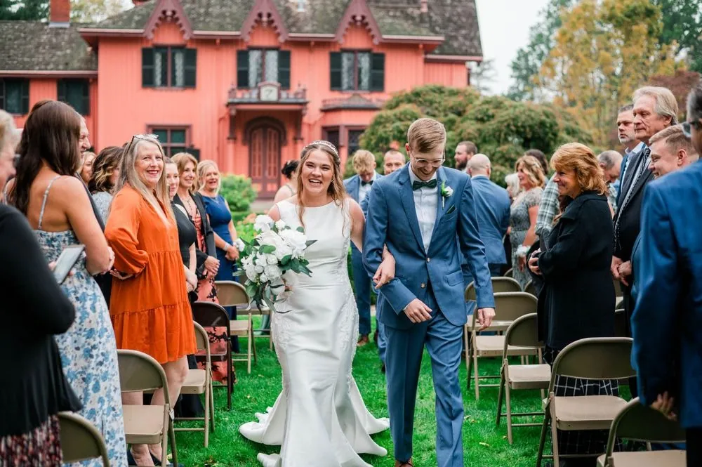 The newlyweds walk back up the aisle as guests smile and clap