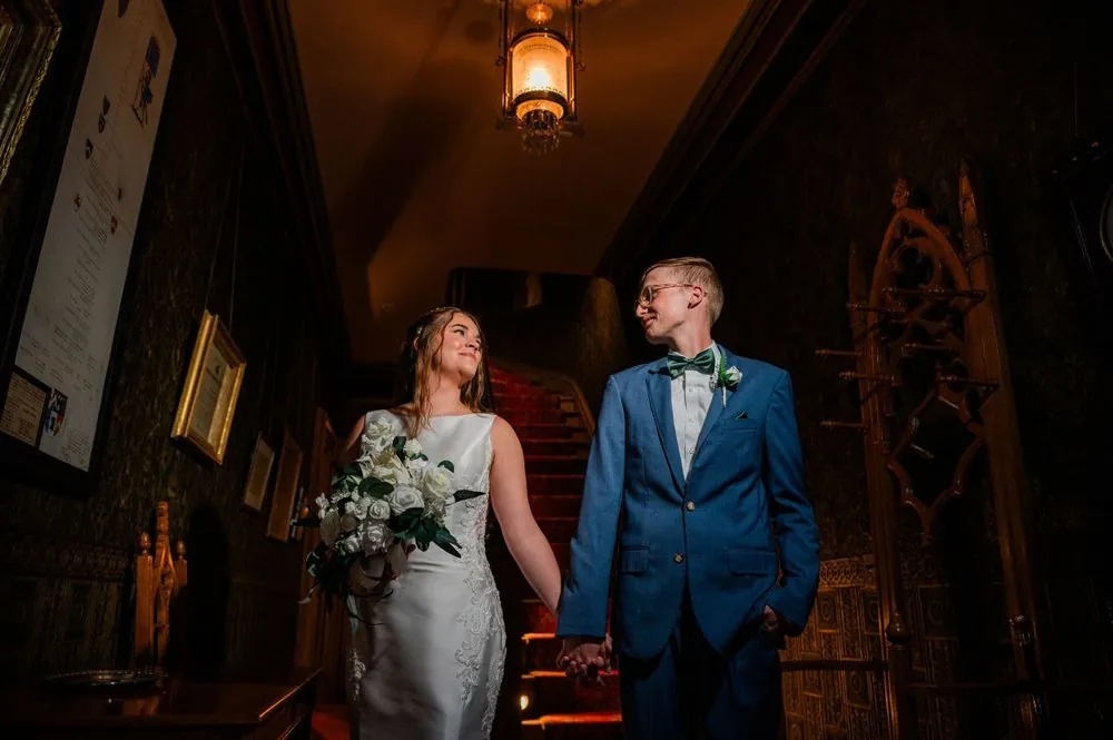 The couple walks through a dark carved wood room inside the historic house