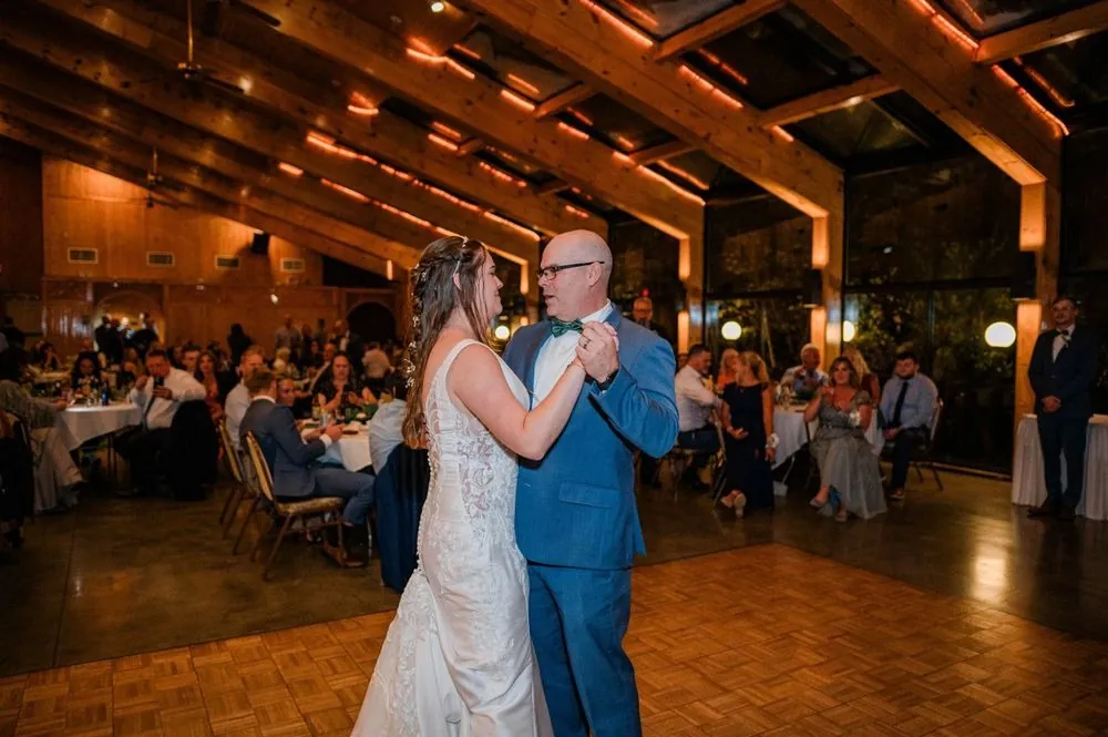 The couple shares their first dance on a parquet floor under warm lights