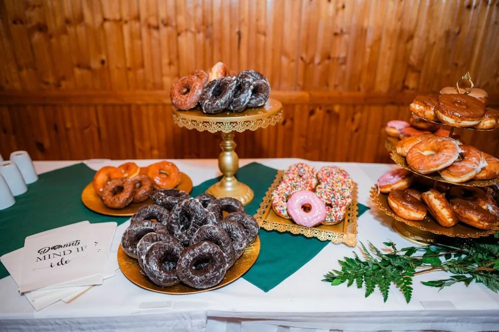 A dessert table stacked with frosted and sprinkled donuts on gold stands