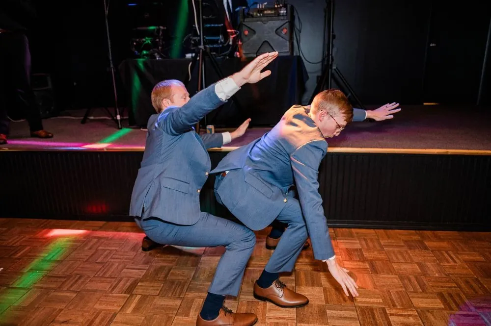 Two groomsmen square off in a dance-off on the lit dance floor