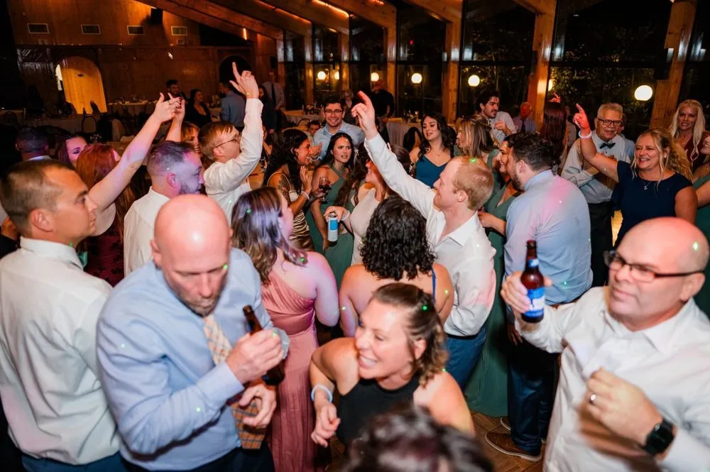 Guests pack the dance floor with arms raised under colored lights