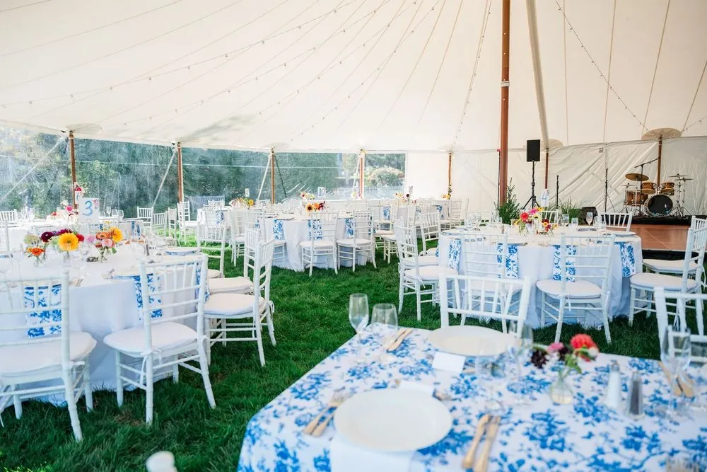 Sailcloth tent set with blue and white floral linens and white chairs on the lawn