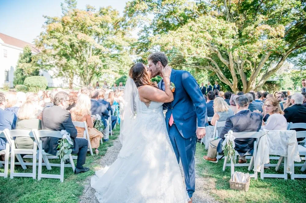 The couple kisses at the end of the aisle as guests cheer