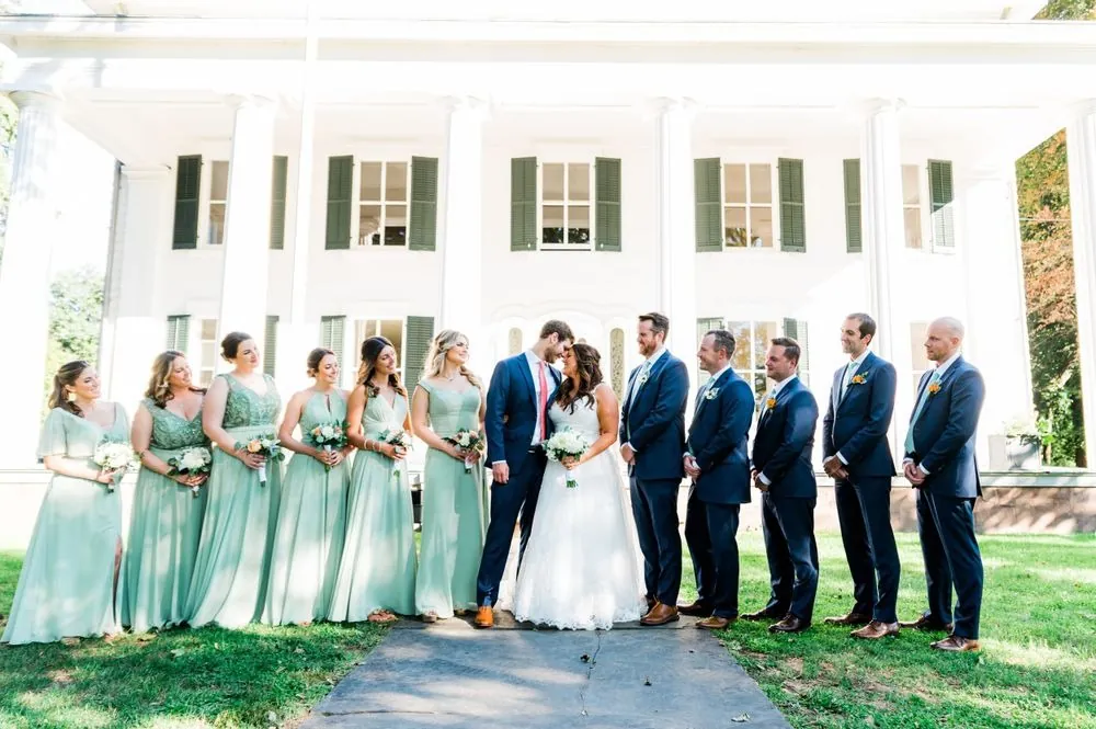 The full wedding party lined up in front of the mansion's white columns