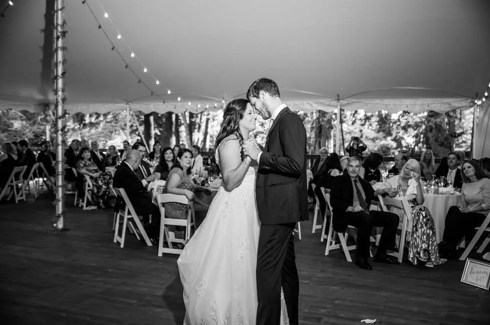 Black and white frame of the first dance under string lights in the tent