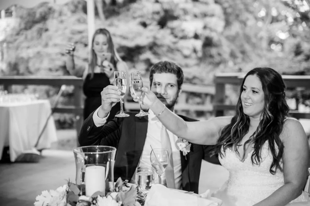 Black and white frame of the couple raising glasses during the toasts