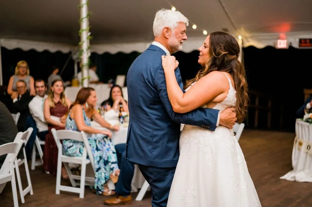The bride slow dances with a silver-haired guest in the tent as others watch