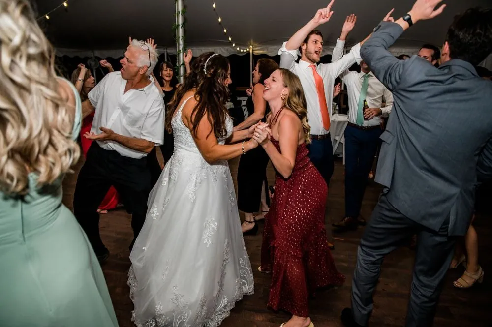 Guests surround the bride on the dance floor with hands in the air