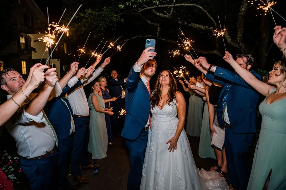 The couple walks through a tunnel of sparklers held by guests at night
