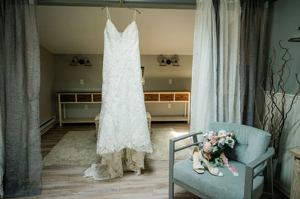 Lace wedding gown hanging in the bridal suite beside a pale blue armchair