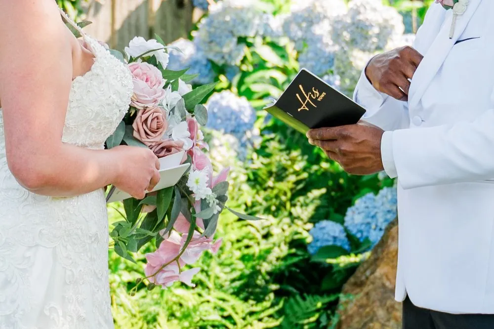 Close view of the couple reading private vows from small books among blue hydrangeas