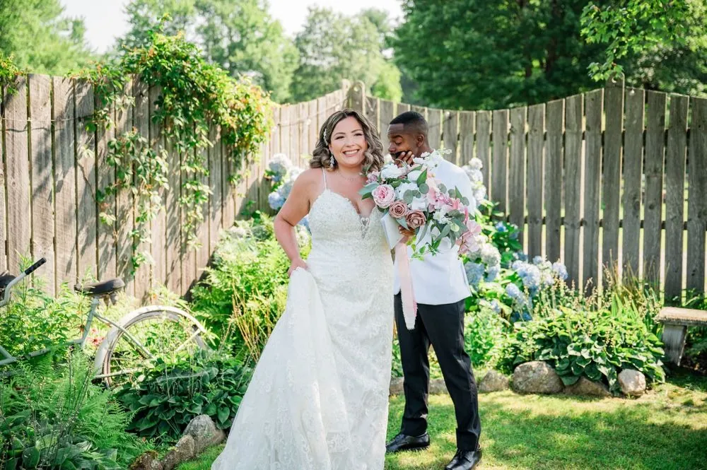 Jhamar and Tifany laugh together in the garden beside a wooden fence